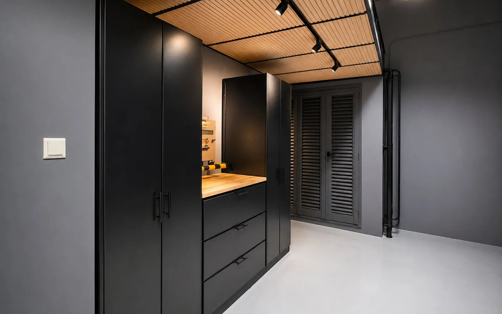 Finished garage cabinetry beneath a timber mezzanine soffit with track lighting